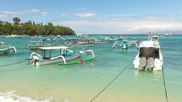 Aerial low pass/flyby of boats over pristine water at  jetty at Padang Bai, Bali, Indonesia. July 2019. afternoon.