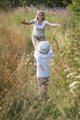 Happy family mother and son enjoying walk together at meadow in summer