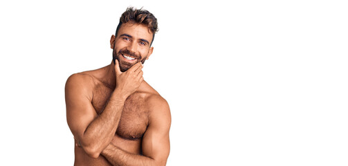 Young hispanic man wearing swimwear shirtless looking confident at the camera smiling with crossed...