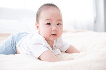 Portrait of a crawling baby on the bed. Happy asian infant in bedroom.