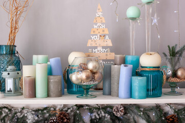 Decor fireplace candles and fir branches. Close up. Glass vase with Christmas decor on fireplace in room. Christmas decoration close-up on table. Details Scandinavian living room for Christmas.