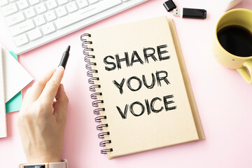 note with the message of share your voice, with desk background