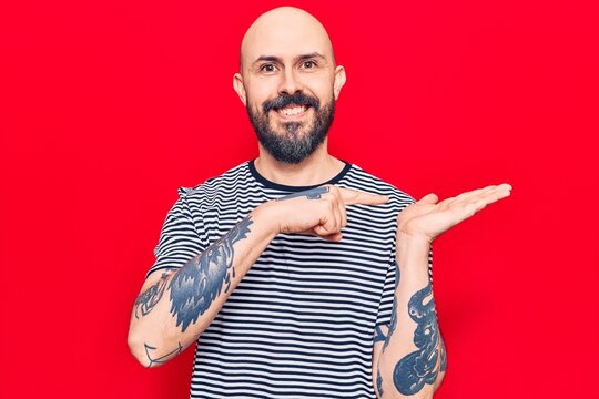 Young handsome man wearing casual clothes amazed and smiling to the camera while presenting with hand and pointing with finger.