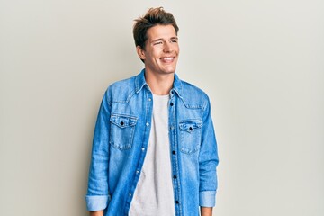 Handsome caucasian man wearing casual denim jacket looking to side, relax profile pose with natural face and confident smile.