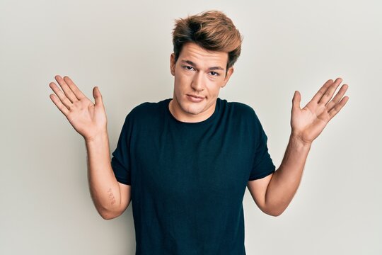Handsome caucasian man wearing casual clothes clueless and confused with open arms, no idea and doubtful face.