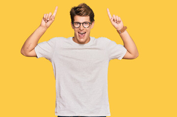 Fototapeta premium Handsome caucasian man wearing casual clothes and glasses smiling amazed and surprised and pointing up with fingers and raised arms.