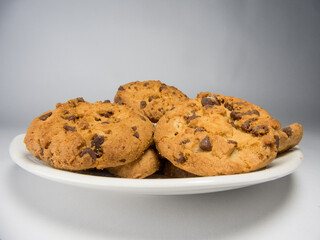 A closeup of freshly baked chocolate chip cookies on a saucer isolated on white background
