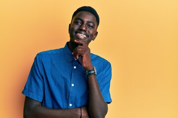 Young african american man wearing casual clothes smiling looking confident at the camera with crossed arms and hand on chin. thinking positive.