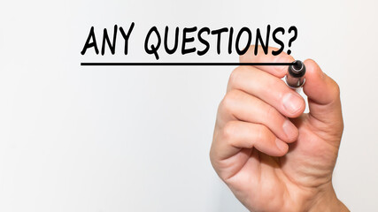 the hand writes text ANY QUESTIONS with a marker on a white background. business concept