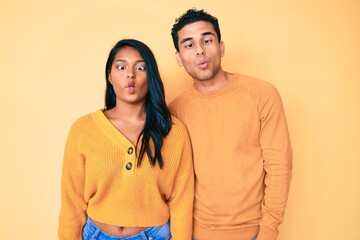 Beautiful latin young couple wearing casual clothes together making fish face with lips, crazy and comical gesture. funny expression.