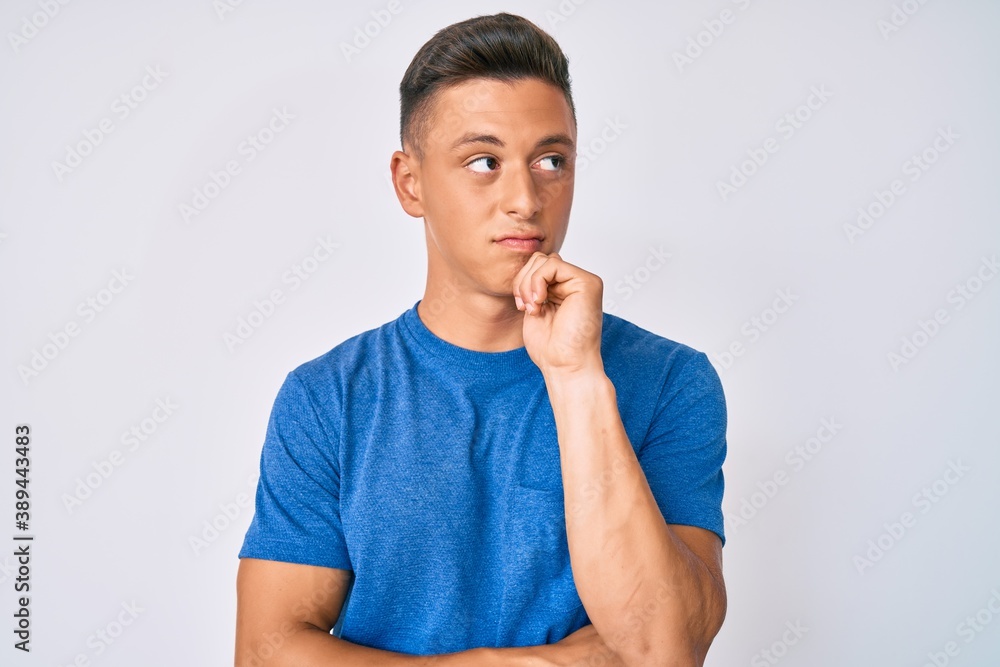 Wall mural Young hispanic boy wearing casual clothes thinking concentrated about doubt with finger on chin and looking up wondering