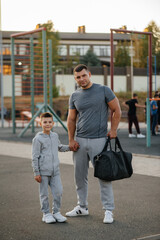 Father and son stand on the sports field after training during sunset. Healthy lifestyle