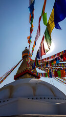 The Bouddhanath Temple in Kathmandu, Nepal. The temple has many colourful prayer flags with 'om mani padme hum' mantra written on them attached to it's golden rooftop. Spirituality and meditation.