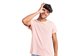 Young hispanic man wearing casual clothes smiling happy doing ok sign with hand on eye looking through fingers