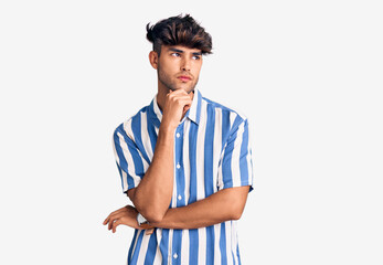 Young hispanic man wearing casual clothes with hand on chin thinking about question, pensive expression. smiling with thoughtful face. doubt concept.