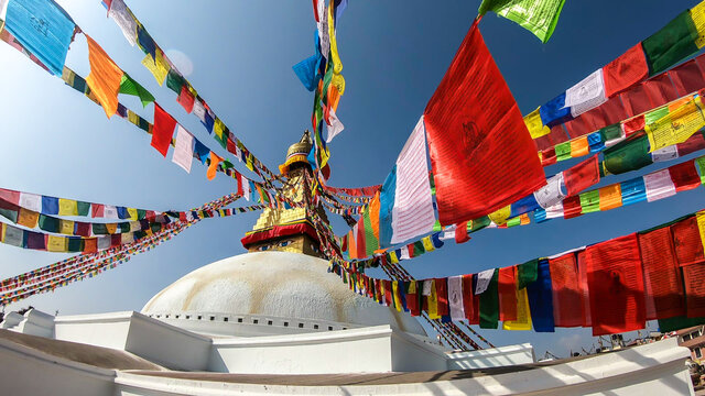 The Bouddhanath Temple in Kathmandu, Nepal. The temple has many colourful prayer flags with 'om mani padme hum' mantra written on them attached to it's golden rooftop. Spirituality and meditation.