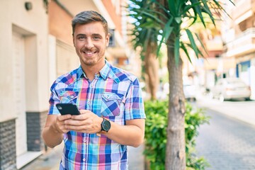 Young caucasian man smiling happy using smartphone at the city.