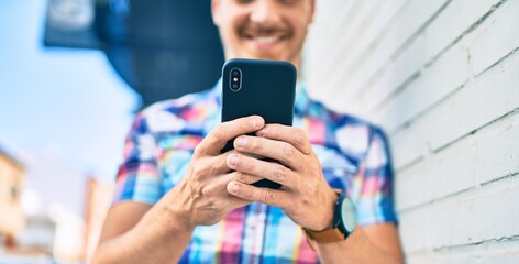 Young caucasian man smiling happy using smartphone at the city.