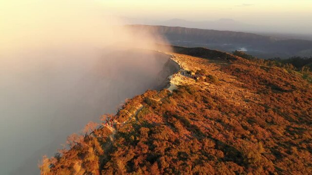 Dramatic sweeping aerial overview of hikers along the smoky caldera of volcano Ijen, Java Island.