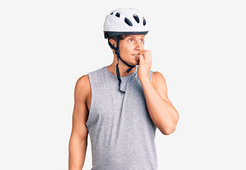 Young handsome man wearing bike helmet looking stressed and nervous with hands on mouth biting nails. anxiety problem.
