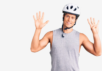 Young handsome man wearing bike helmet showing and pointing up with fingers number nine while smiling confident and happy.