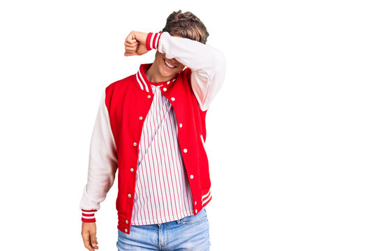 Young handsome man wearing baseball uniform covering eyes with arm smiling cheerful and funny. blind concept.