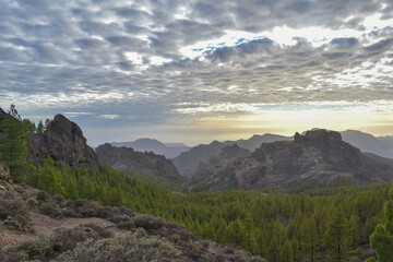 Valley full of mountains, trees and covered with a cloudy sky.
