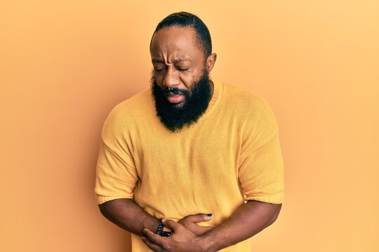 Young african american man wearing casual clothes with hand on stomach because nausea, painful disease feeling unwell. ache concept.