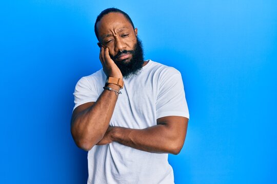 Young african american man wearing casual white tshirt thinking looking tired and bored with depression problems with crossed arms.