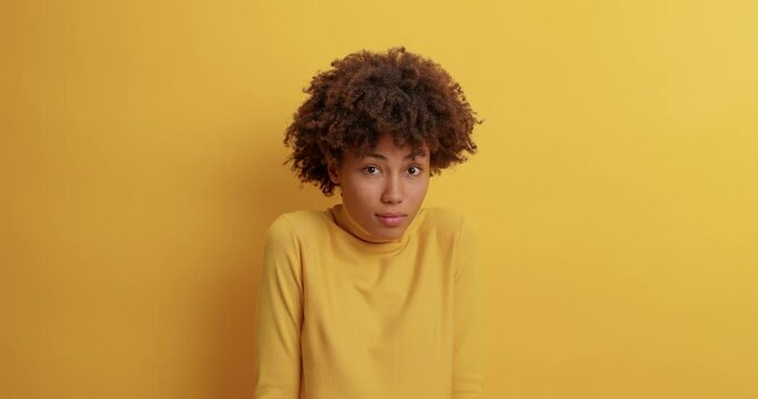Anxious woman looks with fright and anticipation of something bad happen stares intensed then relaxes and sighs with relief expresses different emotions dressed casually poses over yellow wall