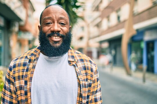 Handsome modern african american man with beard smiling positive standing at the street