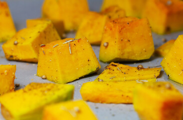 Diced pumpkin on a baking sheet. Pumpkin cooked in the oven. Macro photography of food. A traditional autumn dish of baked pumpkin. Close-up.Raw pumpkin.