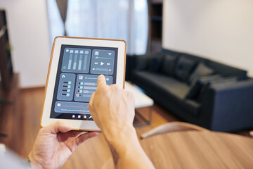 Hands of man controlling smart home through application on tablet computer