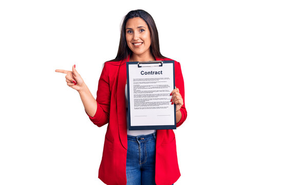 Young beautiful brunette woman holding clipboard with contract smiling happy pointing with hand and finger to the side
