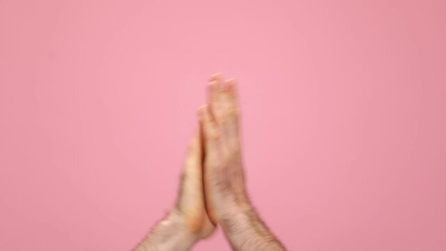 man holding arms in the air, pointing fingers and applauding on pink background in studio