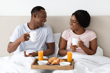Loving african american family having breakfast in bed