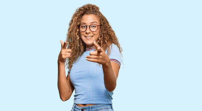 Beautiful caucasian teenager girl wearing casual clothes and glasses pointing fingers to camera with happy and funny face. good energy and vibes.