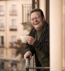 lifestyle portrait of happy and cheerful mature man 65 to 70 years old at home balcony feeling positive and relaxed drinking coffee enjoying retirement smiling to the street view