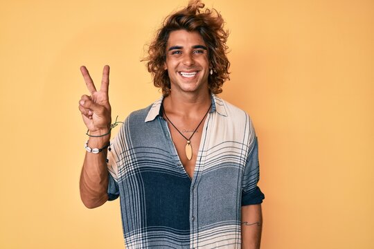 Young hispanic man wearing summer style smiling with happy face winking at the camera doing victory sign. number two.
