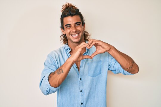 Young hispanic man wearing summer style smiling in love showing heart symbol and shape with hands. romantic concept.