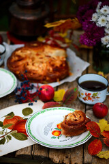 Apple buns with caramel on a wooden table in an autumn garden