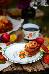 Apple buns with caramel on a wooden table in an autumn garden