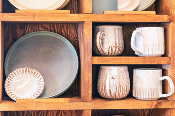 ceramic plates and mugs on a wooden shelf