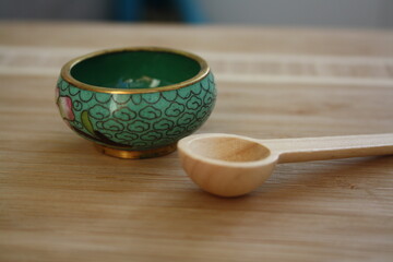 Small bowl and wooden spoon on wooden background