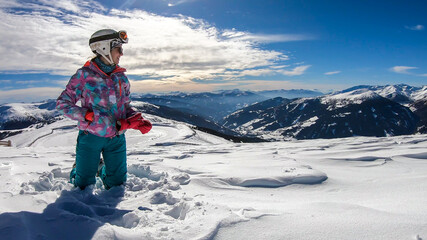 A woman sprinkling powder snow around her on top of Katschberg in Austria. She is happy and joyful. Panoramic view on the surrounding mountains. Winter wonderland, Clear and sunny winter day