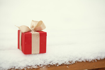red Christmas gift box in the winter snow outdoors.