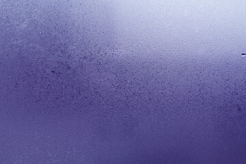 Closeup photo of a foggy window glass in drops of water.