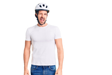 Young handsome man wearing bike helmet winking looking at the camera with sexy expression, cheerful and happy face.