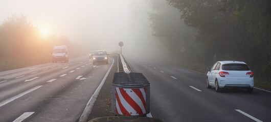 a foggy street with cars early in the morning