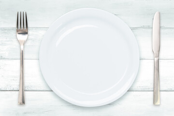 Cooking template - top view of an empty ceramic white plate with cutlery on a wooden vintage table